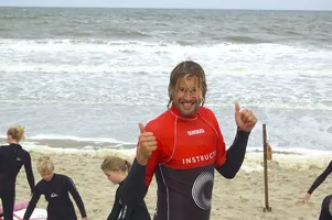 Surf instructeur heeft zijn duimen omhoog