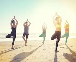 groep meiden doen yoga op het strand